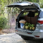 Auto con bagagliaio grande aperto, valigie e passeggino caricati per un viaggio in famiglia