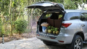 Auto con bagagliaio grande aperto, valigie e passeggino caricati per un viaggio in famiglia